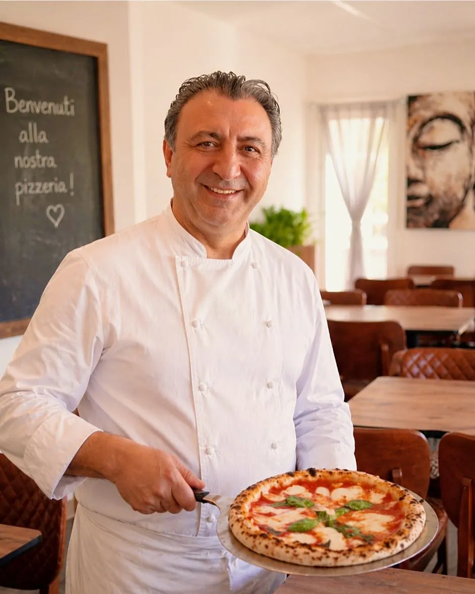 Le chef du Grillon présente une pizza Margherita dans la salle du restaurant